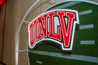 The UNLV Athletics logo over a football field.